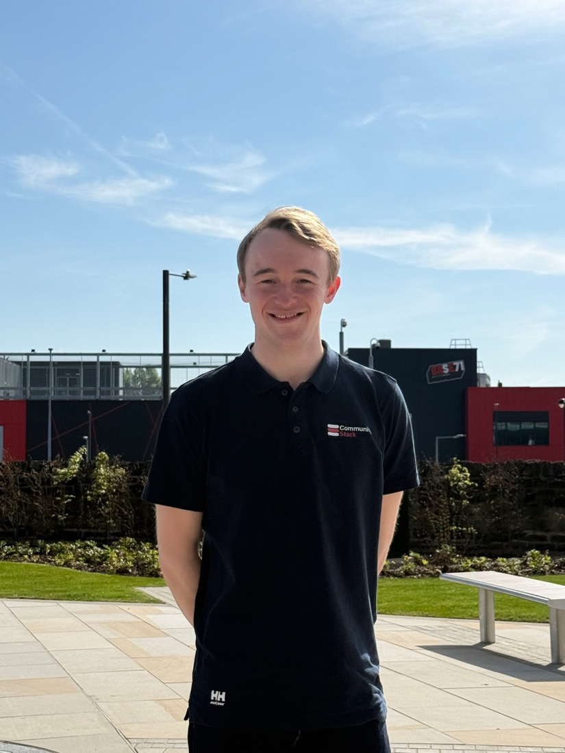 Ethan Sumner, smiling outdoors in a Community Stack polo shirt